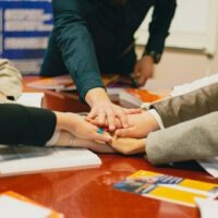 a group of people sitting around a table holding hands